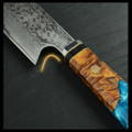 Close-up of blue and wood handle chef's knife with Damascus steel, wood, and resin. Available today at Seido Knives!