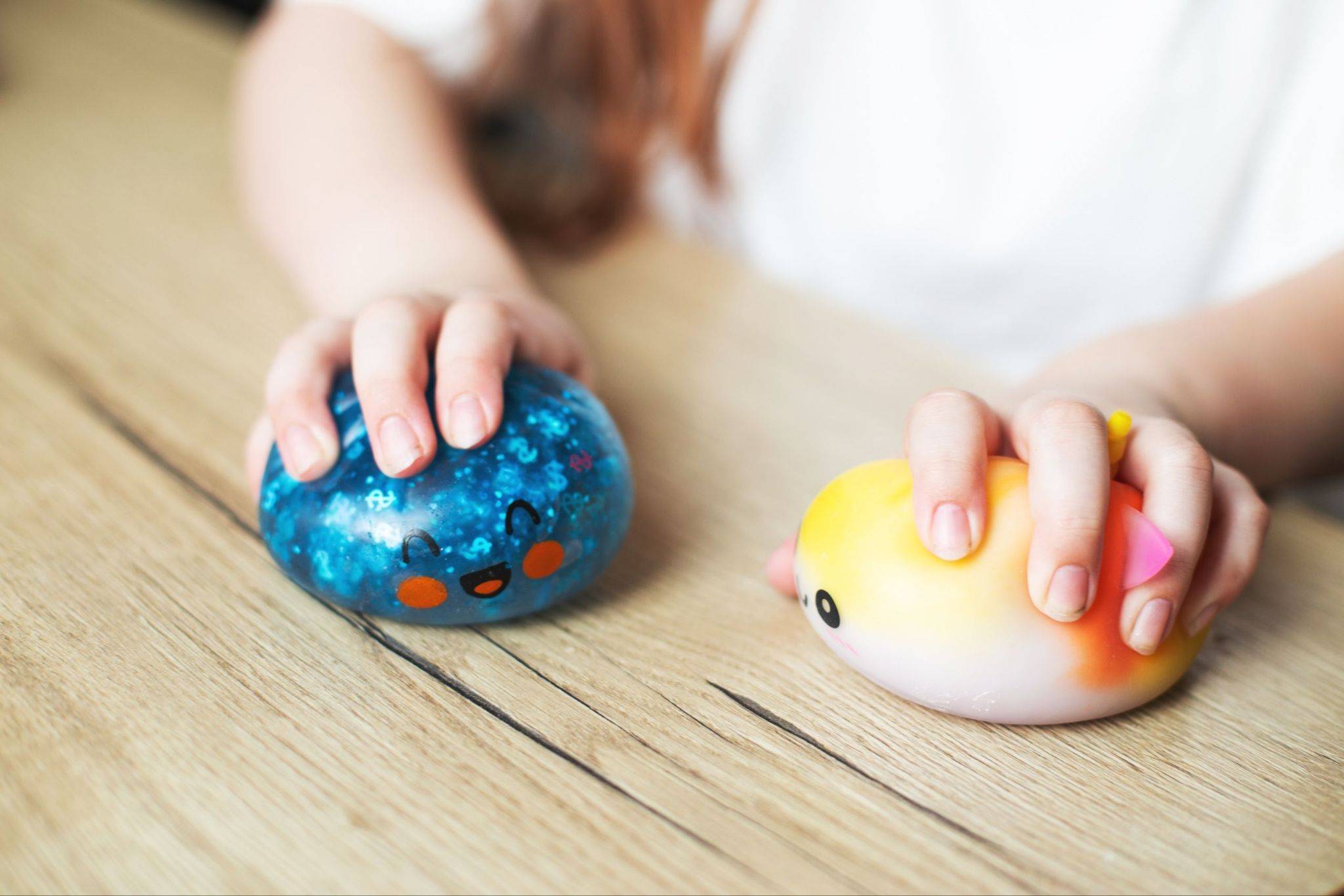 Child hands playing with two colorful squishy toys