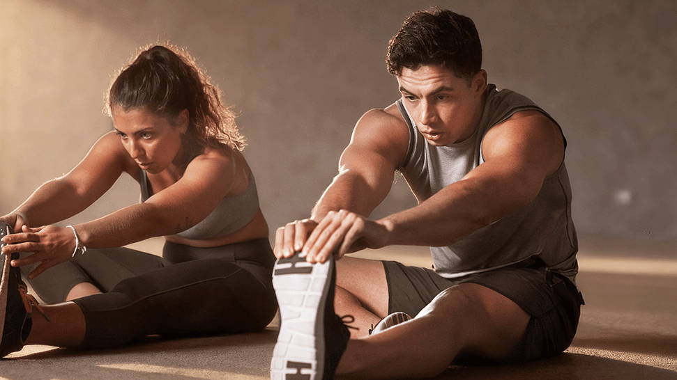 Man and woman stretching after a workout, showing post-exercise muscle soreness in the legs and hips