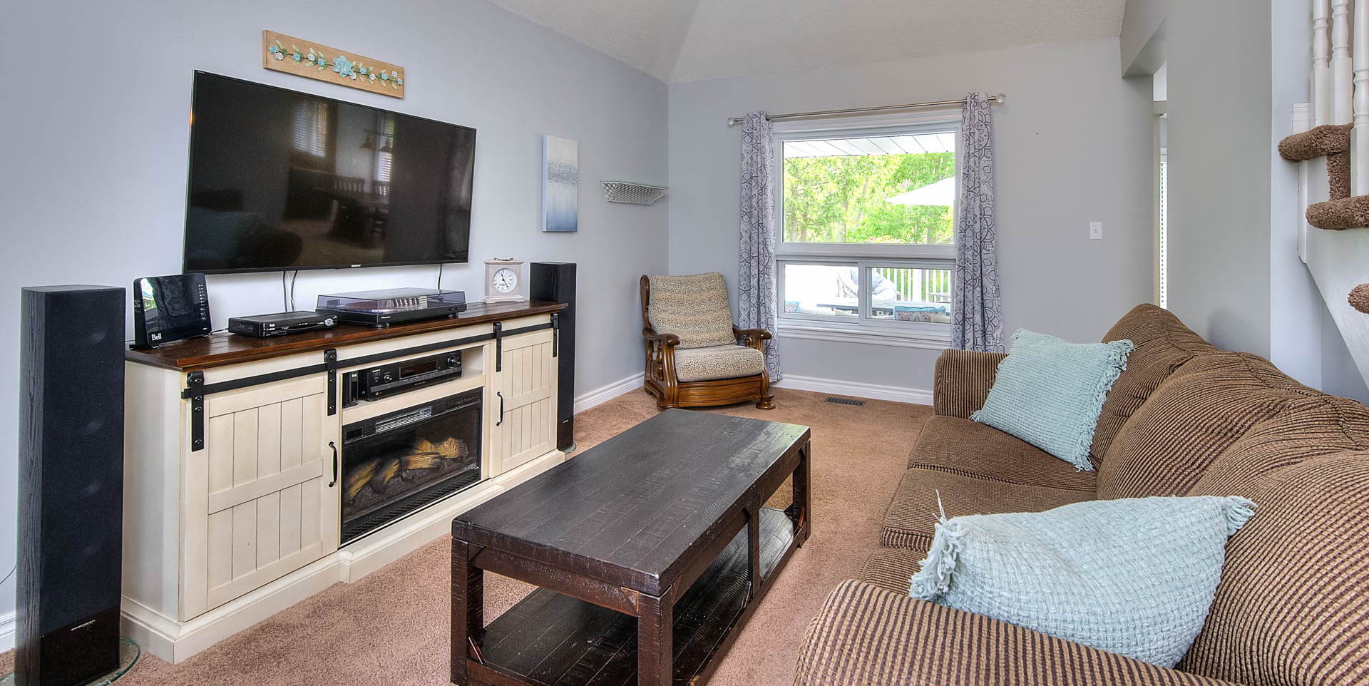 carpeted living room with lofted ceiling, natural light, and TV