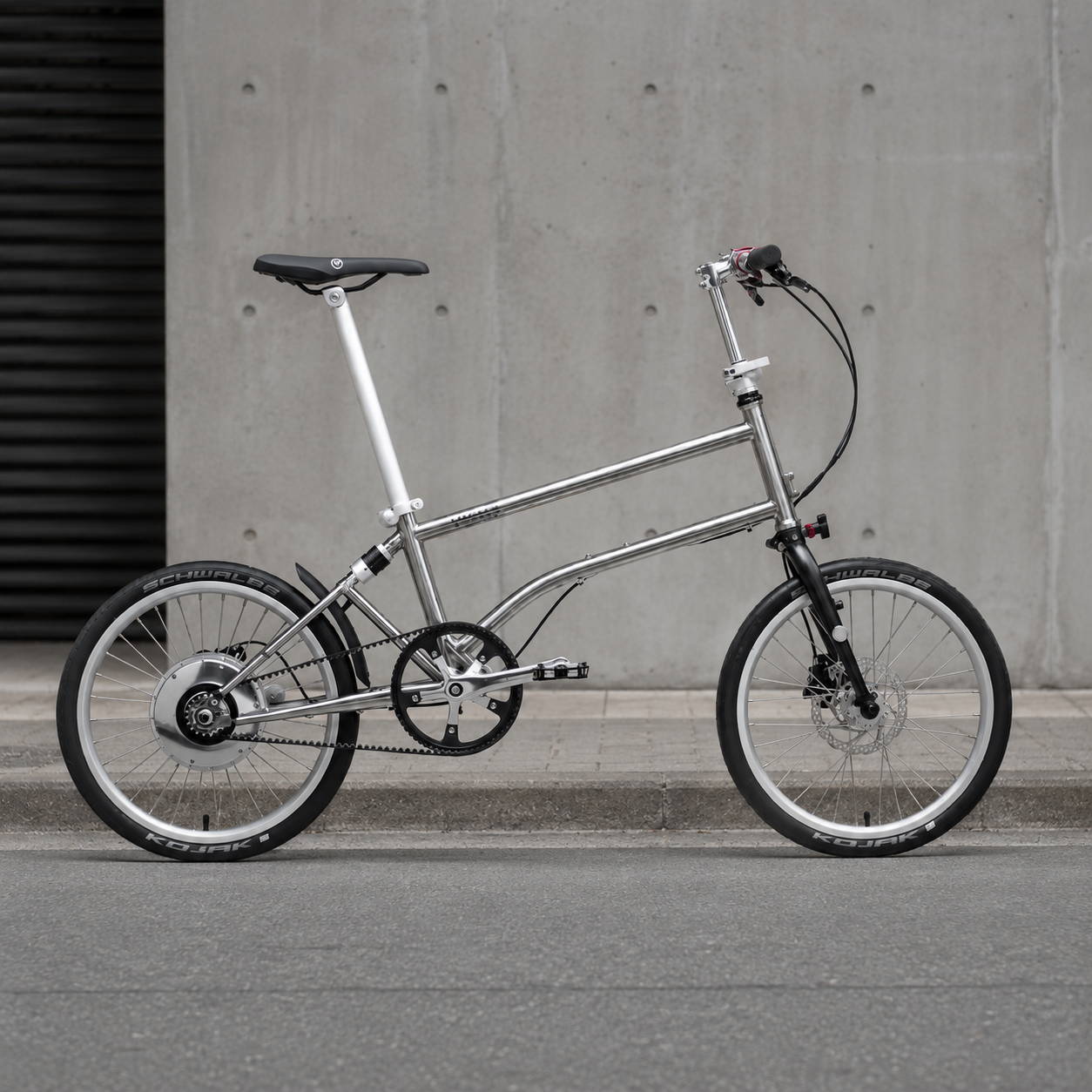 Vello Bike+ Automatic elektrische vouwfiets met titanium frame tegen een industriële betonnen achtergrond