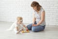 Baby girl solving puzzles independently under while mother is looking at her. 