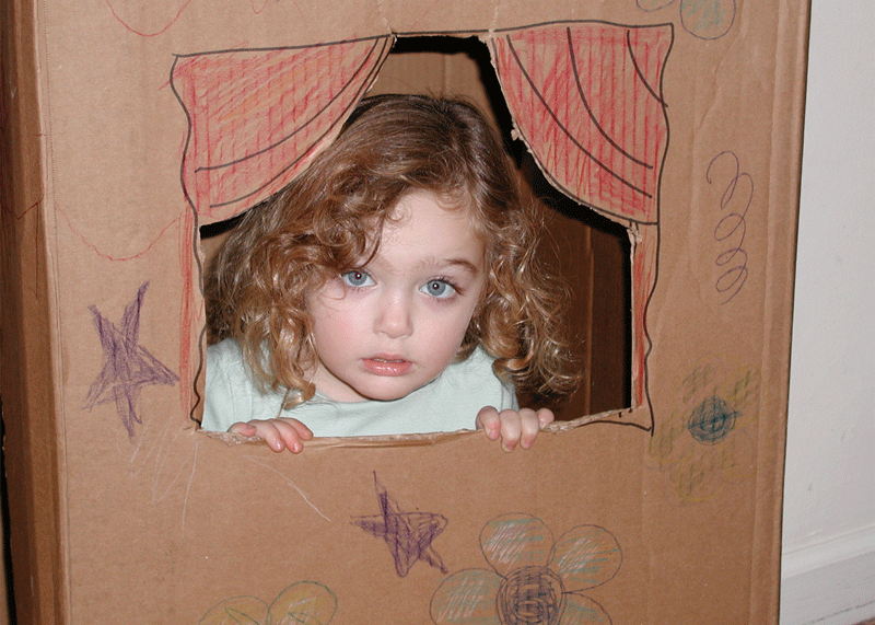 cardboard playhouse with little girl inside