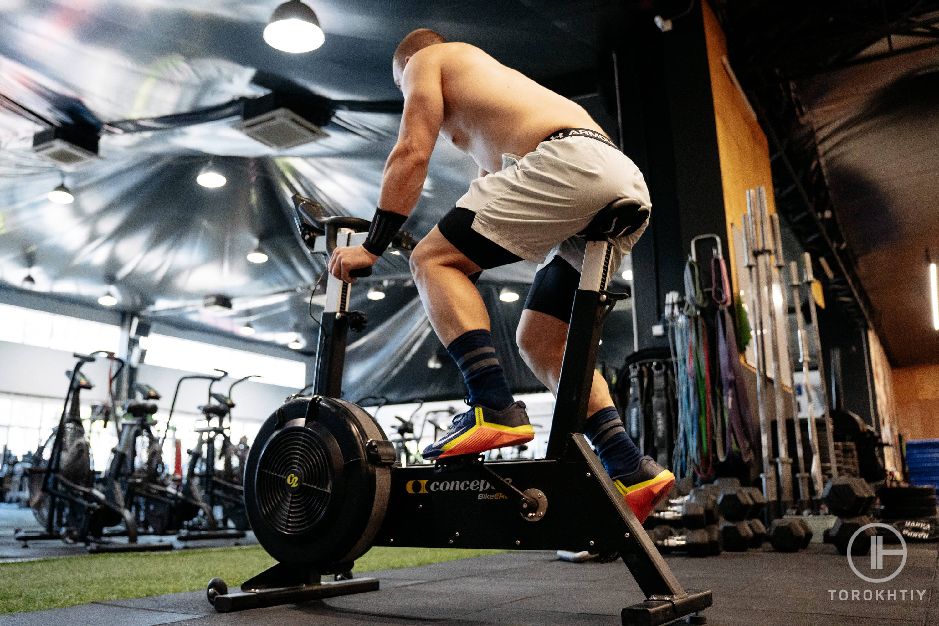 athlete in white shorts training on exercise bike in gym