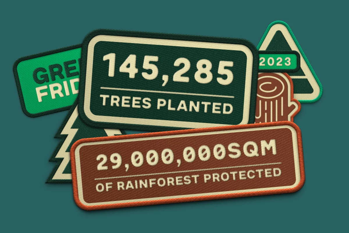 graphics that look like scout badges. the badges say, "145,285 trees planted" and "29,000,000SQM of rainforest protected". "2023". one badge is obscured but assumed to read "Green Friday"