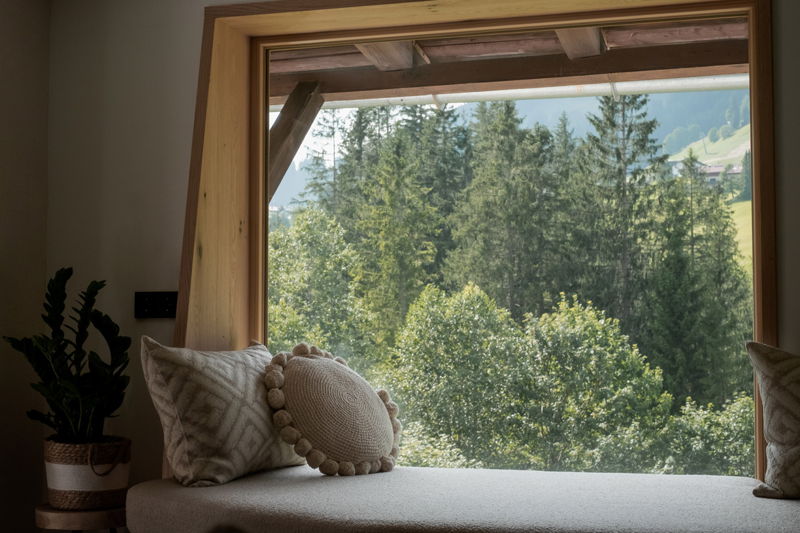 Lieblingsplatz am Fenster mit Blick in den Wald und Berge in Mittelberg im Kleinwalsertal.