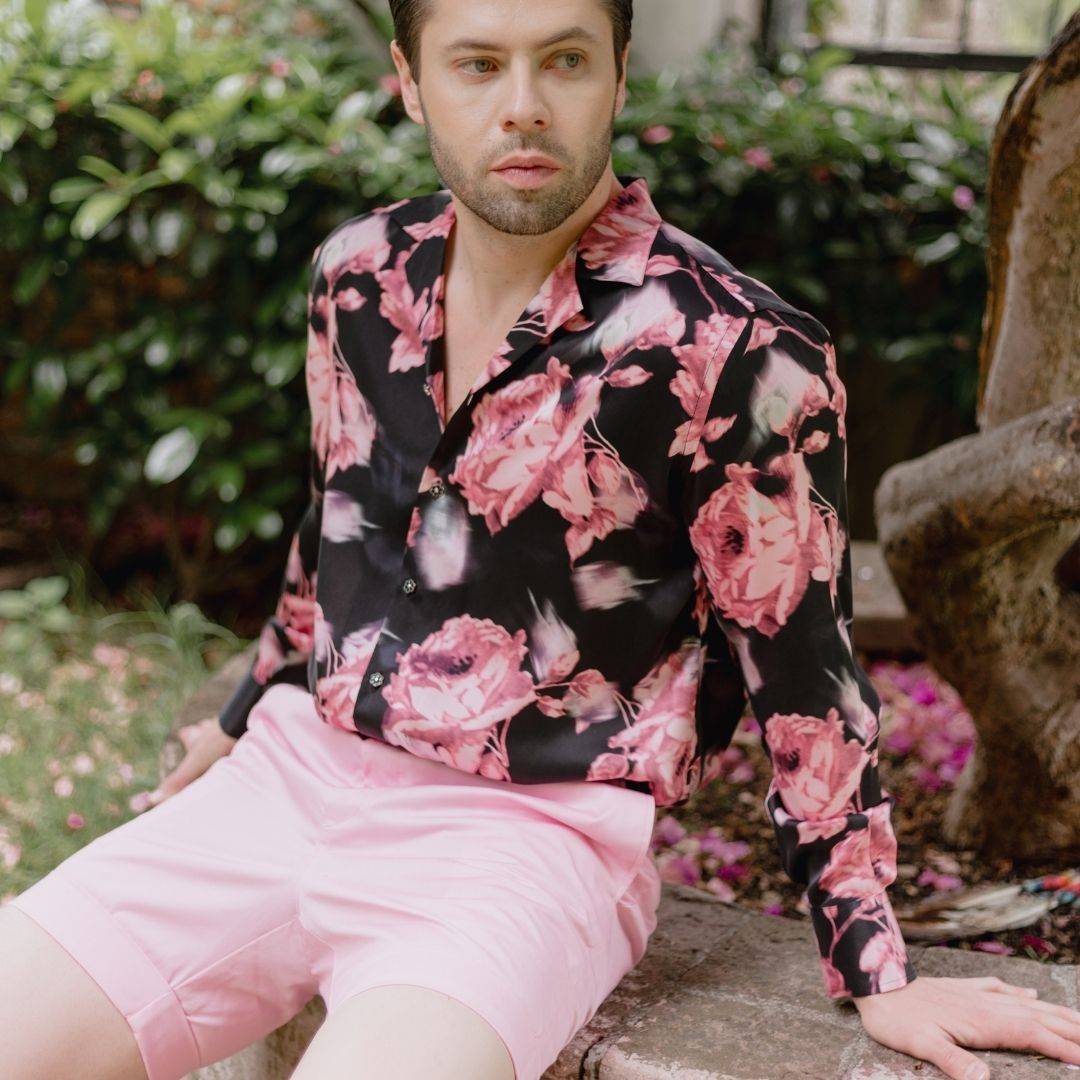 model sitting outside wearing pink shorts and a black and pink floral silk shirt from 1000 kingdoms