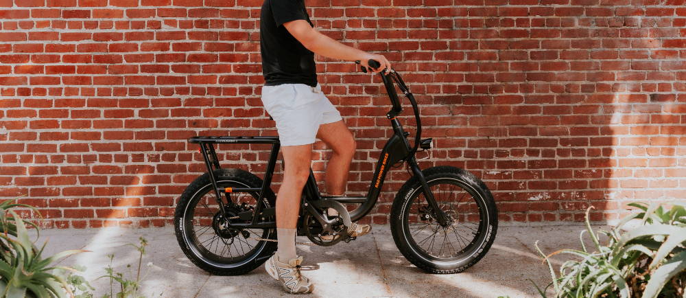 Rider on Rad Power RadRunner 2 e-Bike in front of brick wall