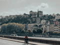Cycliste à Lyon, au bord de la rivière, avec les bâtiments iconiques en arrière plan