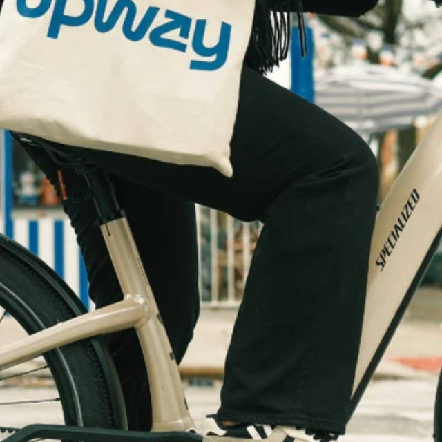a woman riding a specialized step through electric bike and carrying an upway handbag