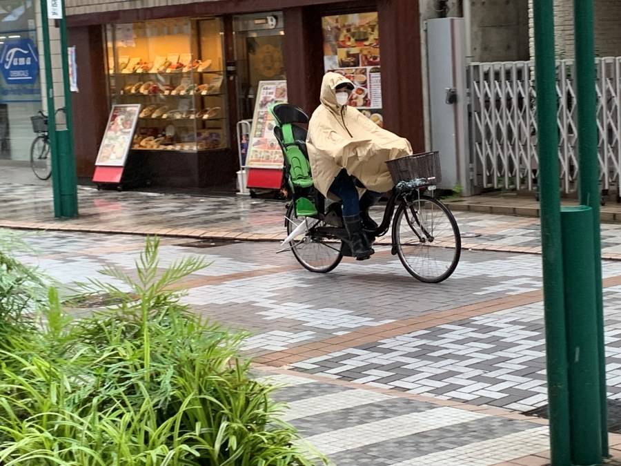 雨合羽を着て自転車に乗る人