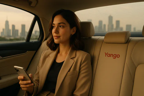 A young woman in a tan blazer sits in the back of a Yango car, looking out the window at a city skyline while holding her phone.