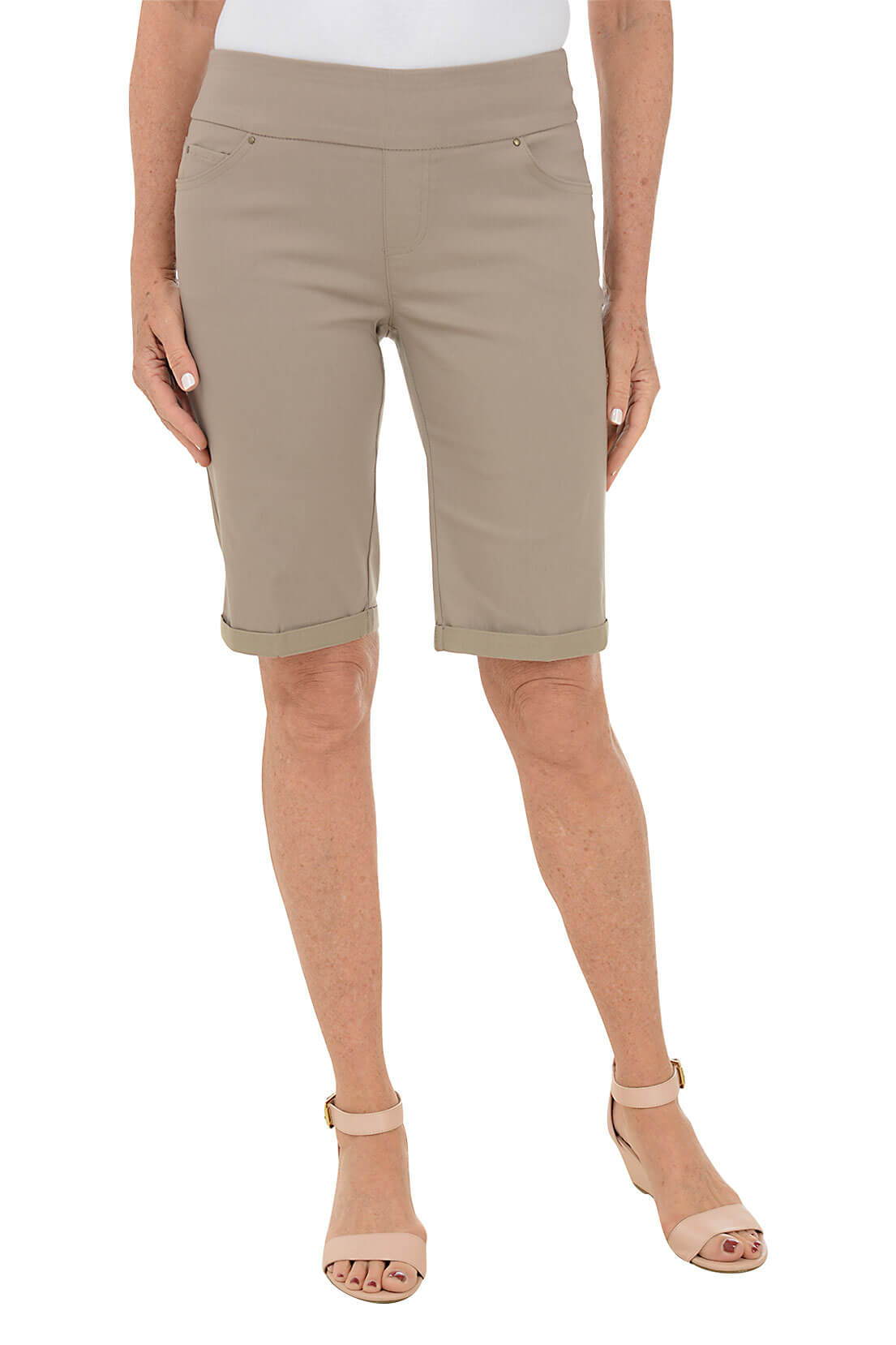 A woman wearing a khaki-colored bermuda short against a white background