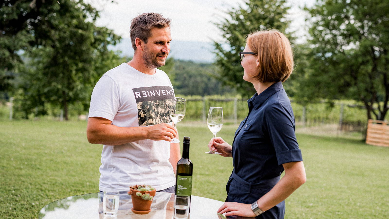 3 Generationen der Familie Trummer auf einer Bank vor dem Weingarten. Ein Bub sitzt im Baum.