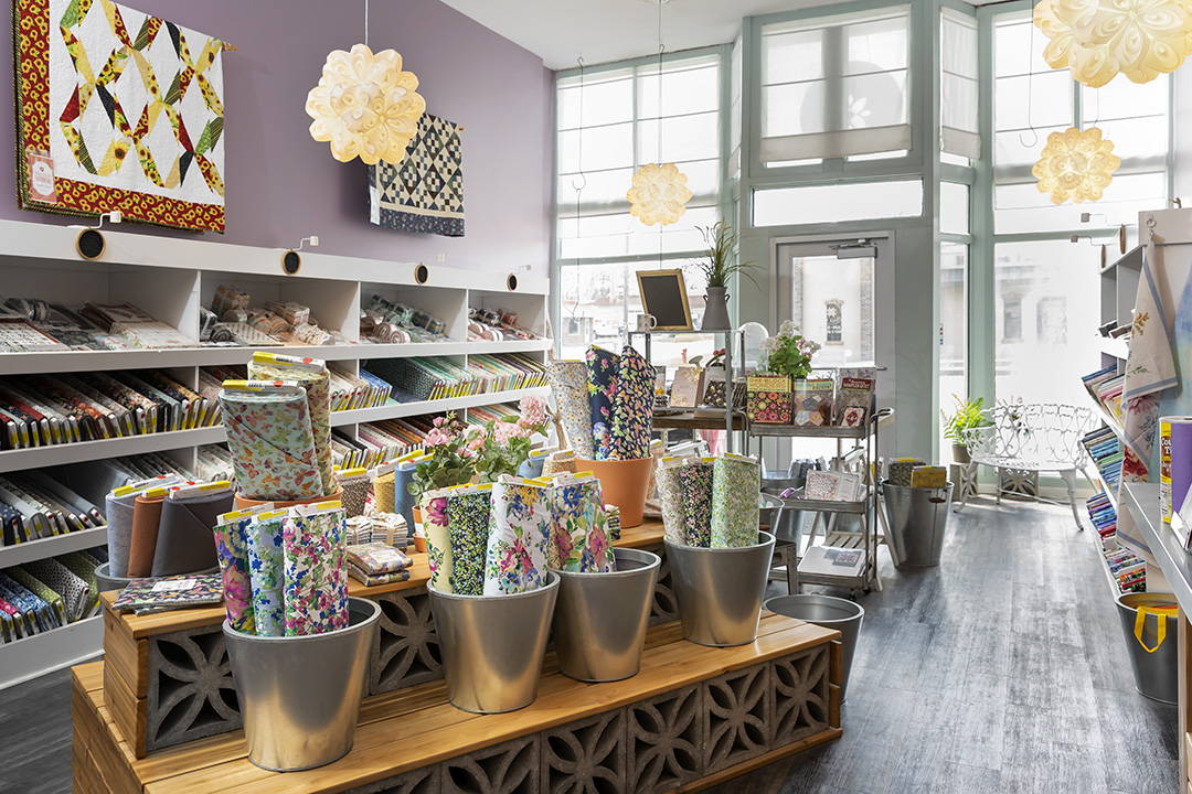 interior photo of the florals fabric shop in hamilton, missouri. there are lots of floral quilt fabrics on bolts as well as display quilts, gifts and notions.
