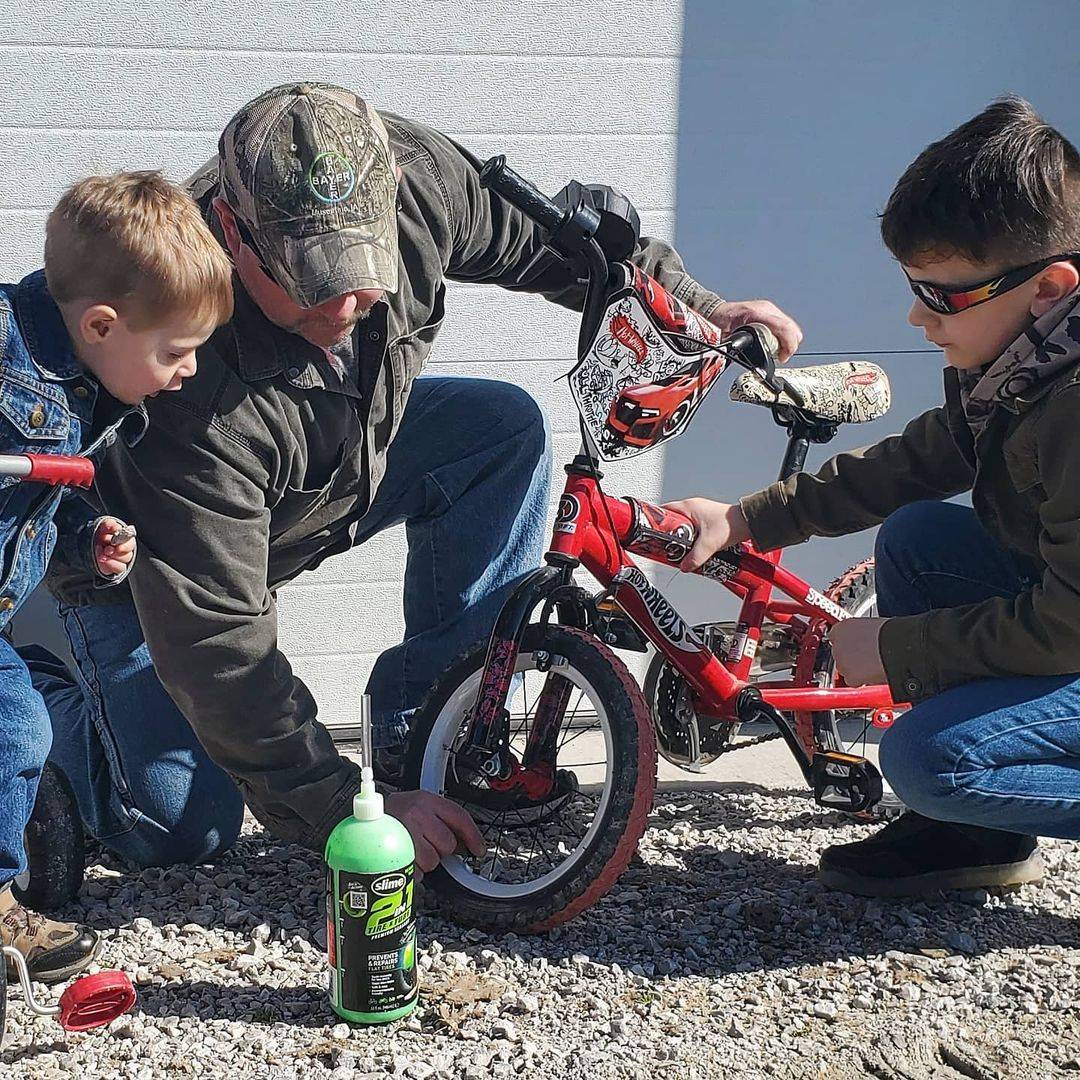 Father Installing Slime 2-in-1 Tire & Tube Sealant into Kids Bike