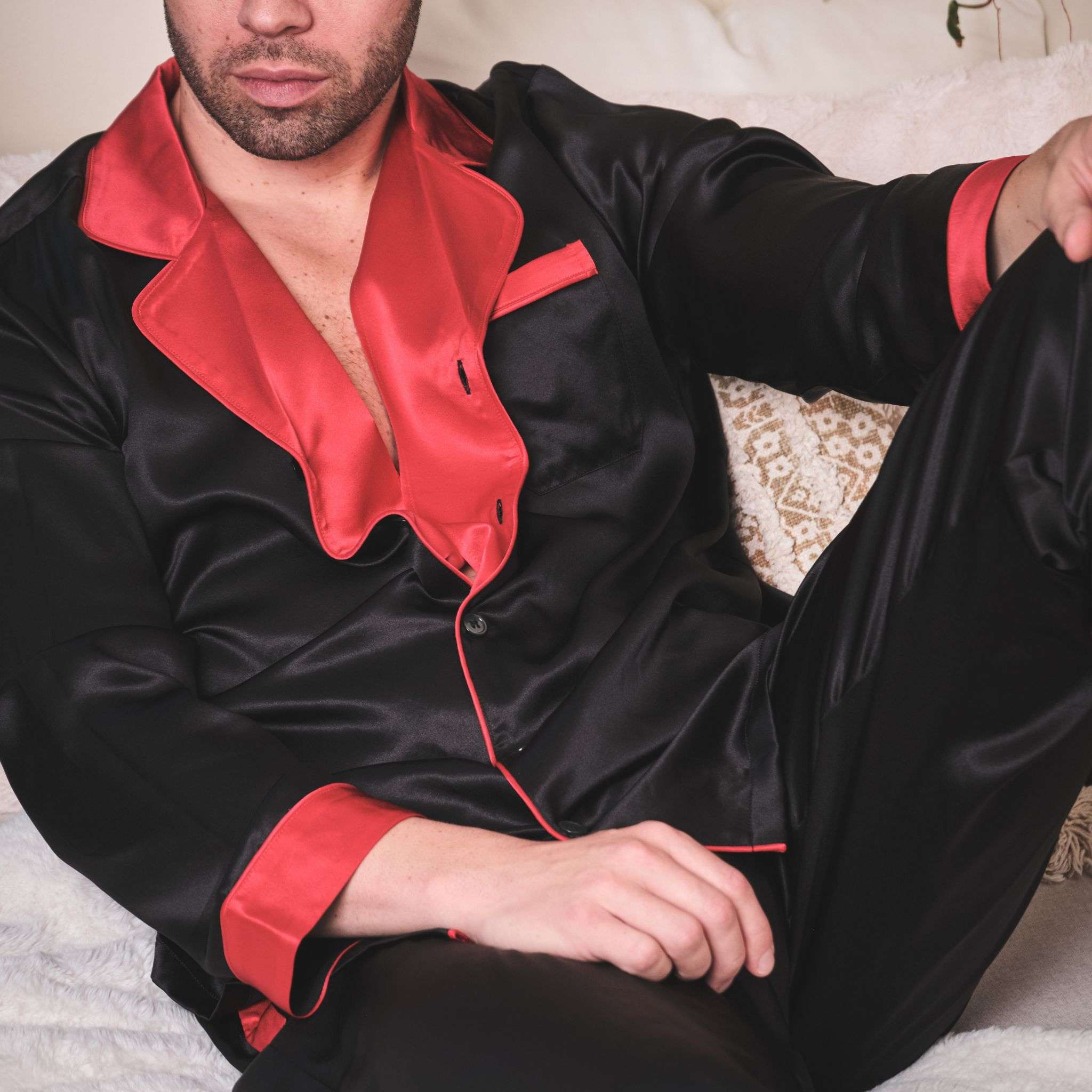 close up on the red collar of a black and red silk pajama set worn by a male model