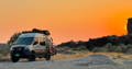 Camper Vans gathered at a campfire at sunset