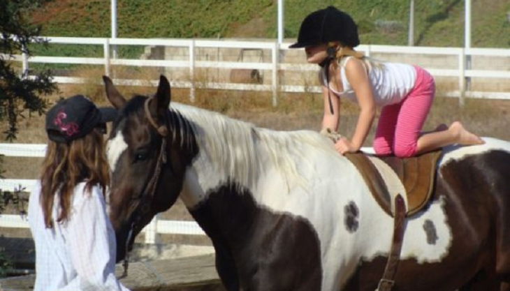 iris brosen kind kniet auf pferderücken