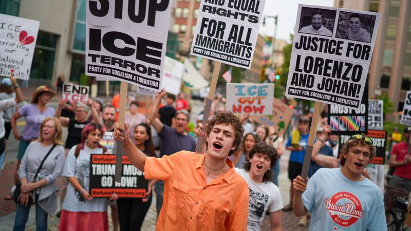Protesters holding signs marching down the street.