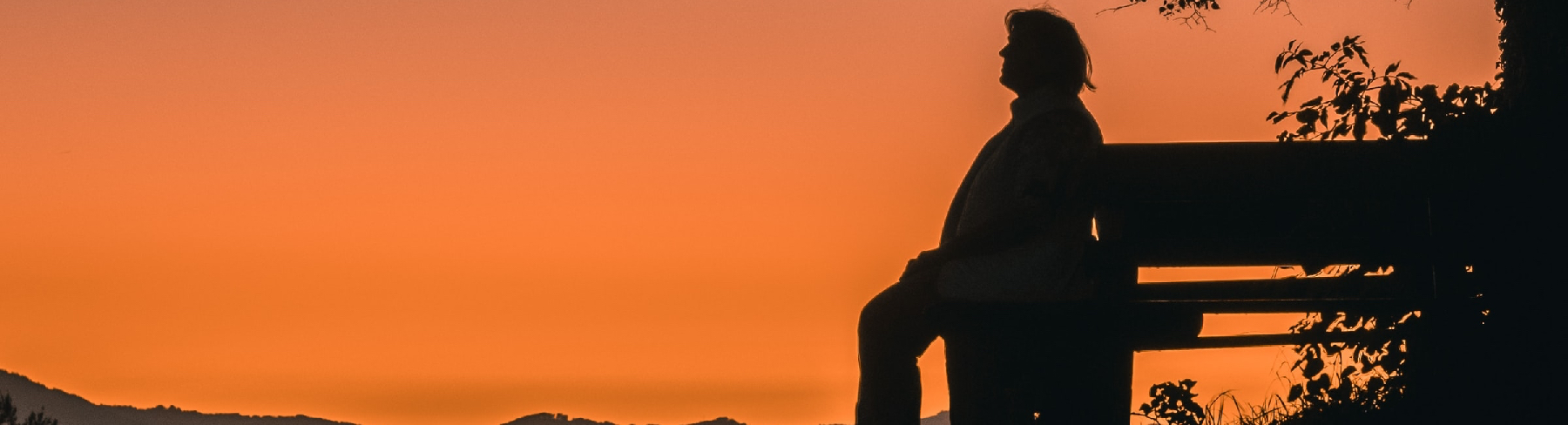 Man sitting patiently on bench in sunset