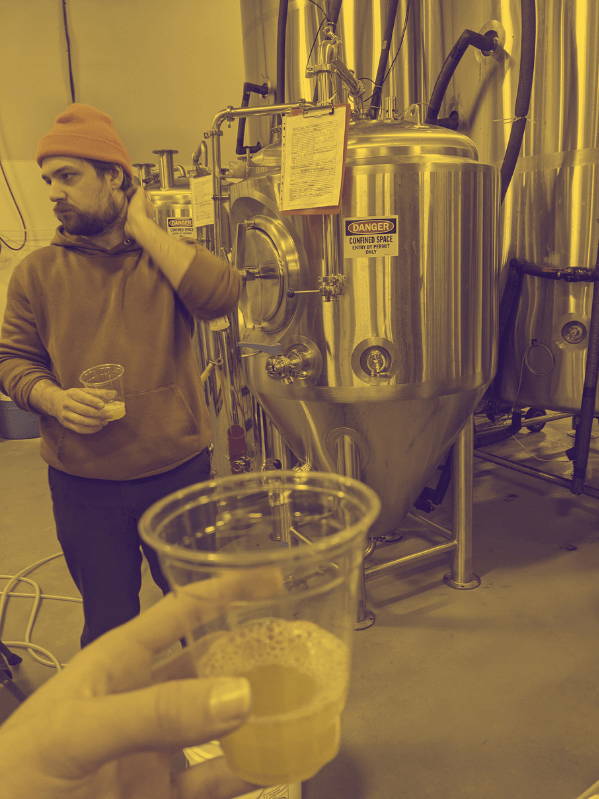 Man standing beside a beer vat.