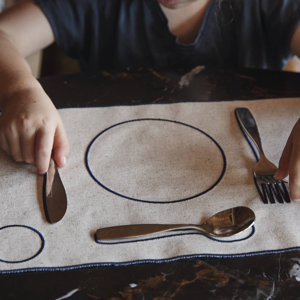 Un petit garçon utilise des couverts enfant pour dresser le couvert