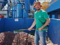 Röster Alois mit einem breiten Lächeln beim Umrühren fermentierter Kaffeekirschen während des Farmbesuchs in Brasilien.