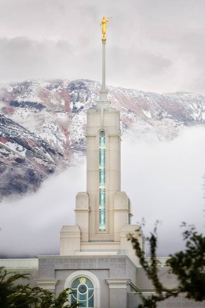 Vertical LDS art close-up photo of the Mt Timpanogos Temple steeple against snowy mountains and clouds. 