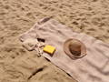 towel on the sand with sunglasses and a hat 
