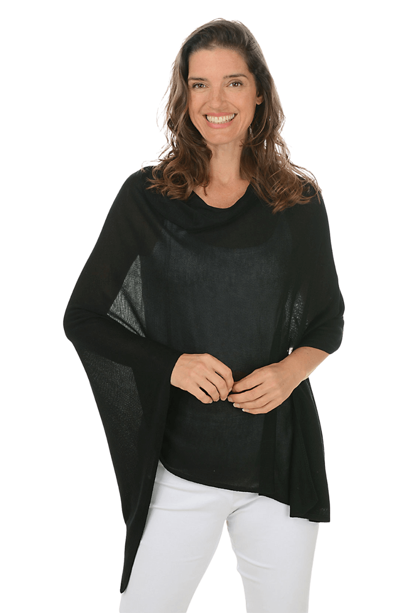 A woman wearing a black poncho and white pants