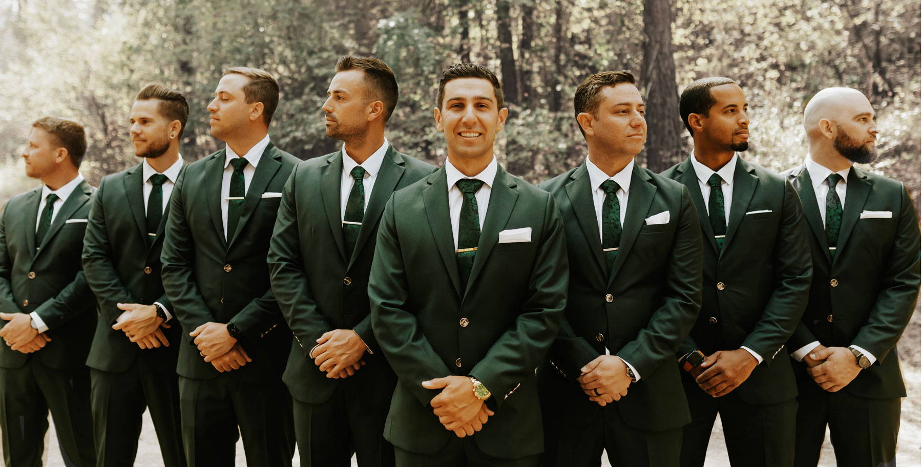 groom and groomsmen in standing in green suits