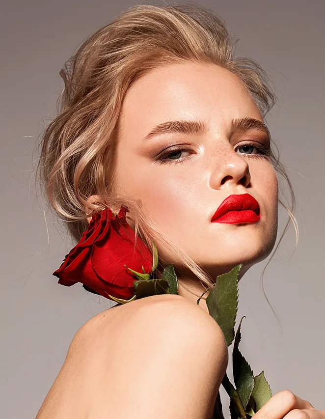 Photo de la jeune fille blonde avec une rose rouge, aux lèvres d'un rouge écarlate.