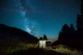 canvas tent lit up at night with mountains and the milky way in the background