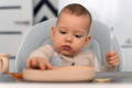 Baby putting a decoration on a birthday cake.