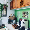 Glass spice jars attached magnetically to a metal backsplash sit in kitchen nook surrounded by a toaster oven, cutting board, coffee maker, and other kitchen items