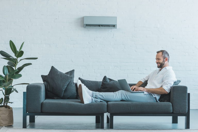 man enjoying nest mini split control working on couch