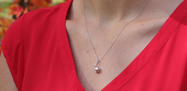 Gold pendant with pink freshwater pearl perched on a rounded double stem.