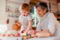 Grandma and granddaughter making dough in the kitchen.