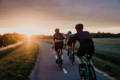 Trois cyclistes sur la route au coucher du soleil