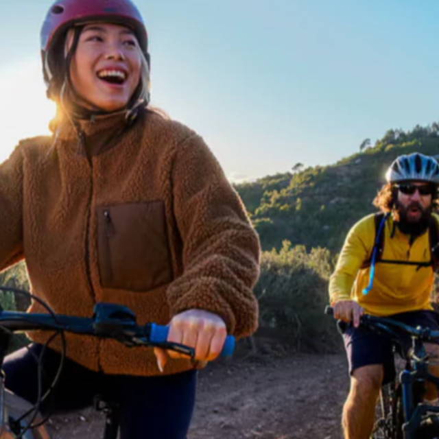 a woman and a man riding electric mountain bikes in the mountains