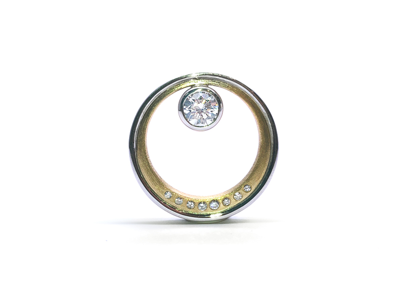 Round pendant in yellow gold with small diamonds on the outline and a large detached insulated diamond in the centre.