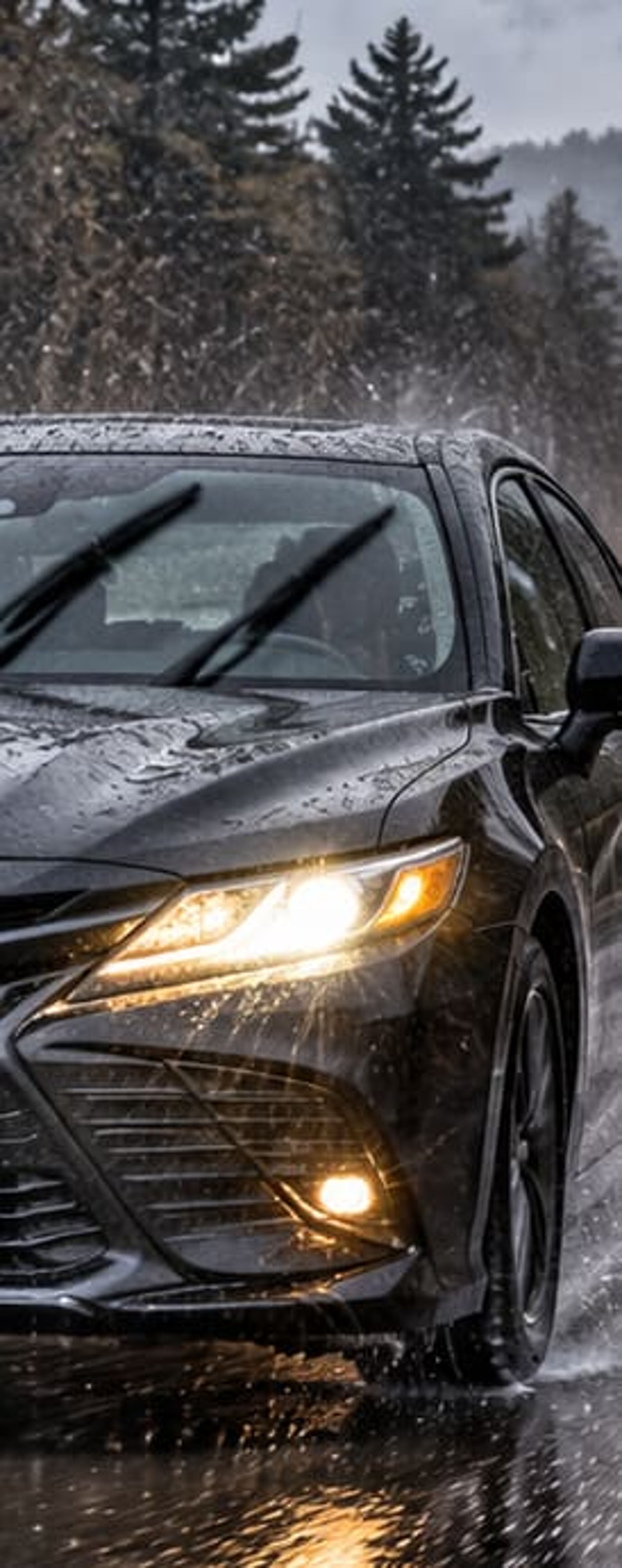 A car driving through heavy rain with headlights on