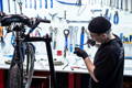 Un mécanicien en train de travailler sun un vélo dans son atelier, avec des outils derrière