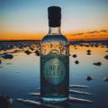 Bouteille de Gin Seaglass posée sur la plage au couché du soleil, distillerie Deerness dans l'archipel des Orcades d'Ecosse