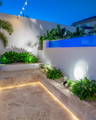 Layered garden lighting with step illumination and soft wall washing creating depth and contrast