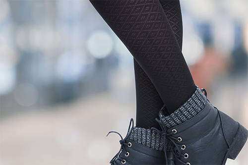 A pair of crossed legs wearing black diamond pattern socks