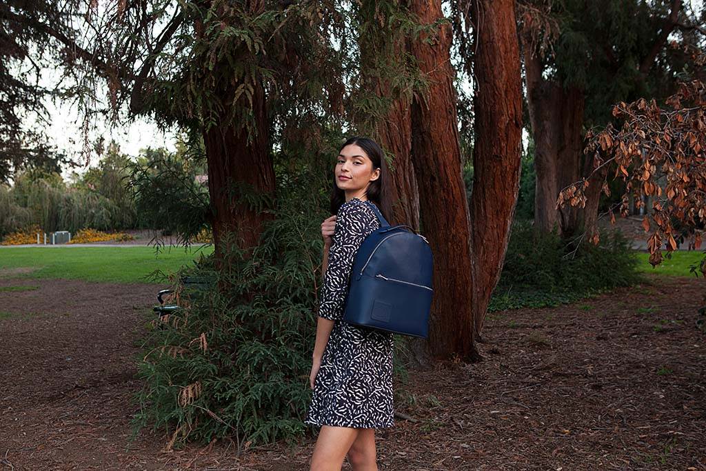 A woman wearing a purple dress wearing an Opus Mind purple bagpack