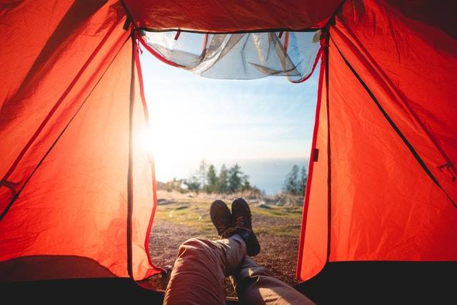 A tent view from the inside. Legs crossed facing a view of the outdoors.