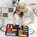 Mother and daughter sitting on the floor and playing with an educational children's toy with zippers, buckles, snap pockets, and shoelaces.